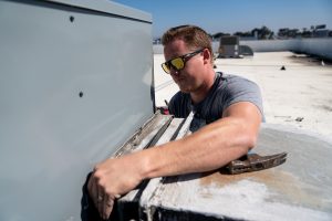 Man working on hvac unit on top of a building 